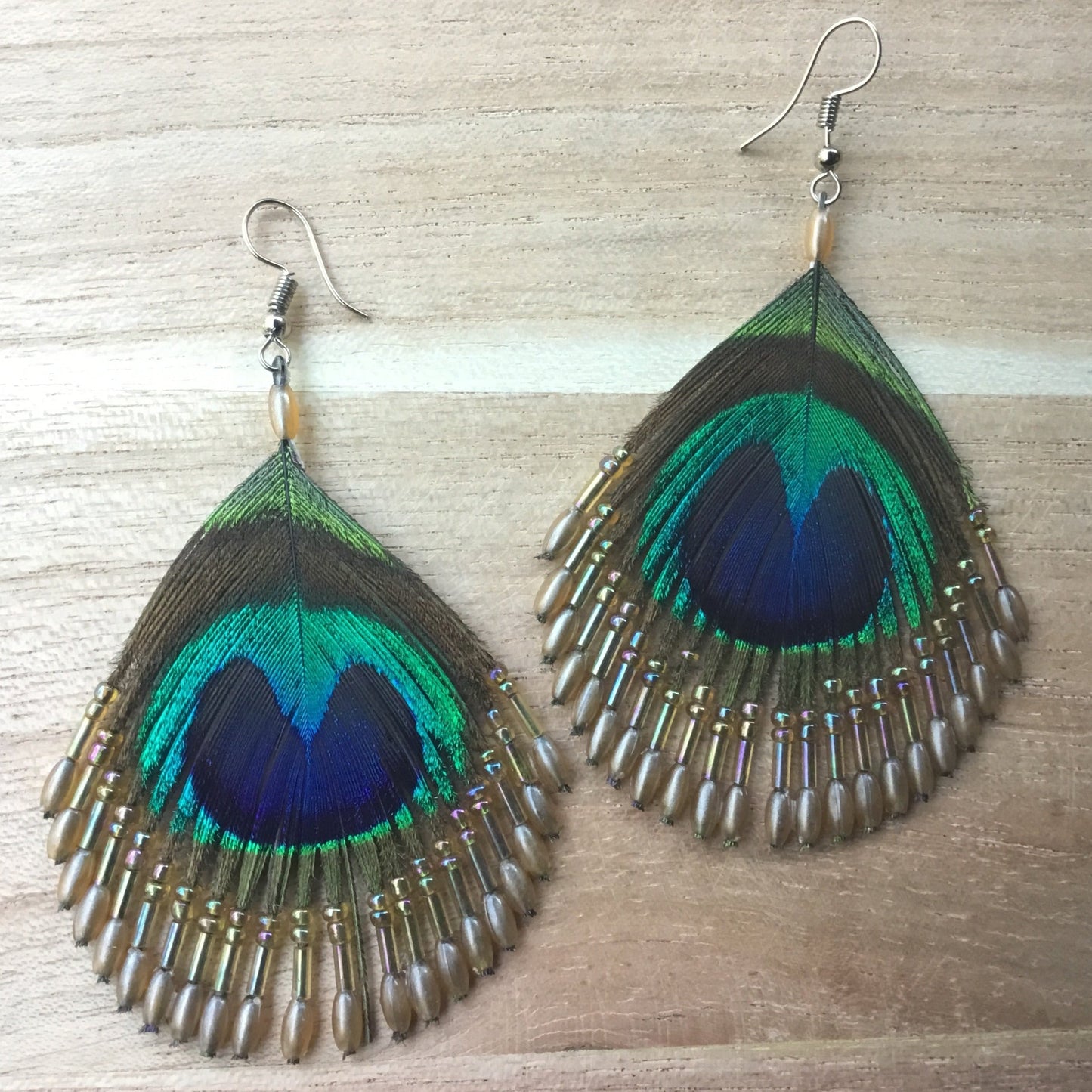 Peacock feather earrings with pearl beads.