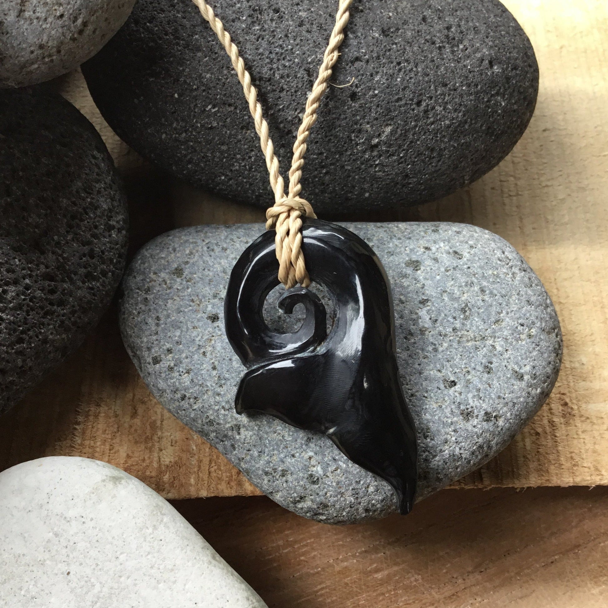 whale necklace, black. carved whale tail.